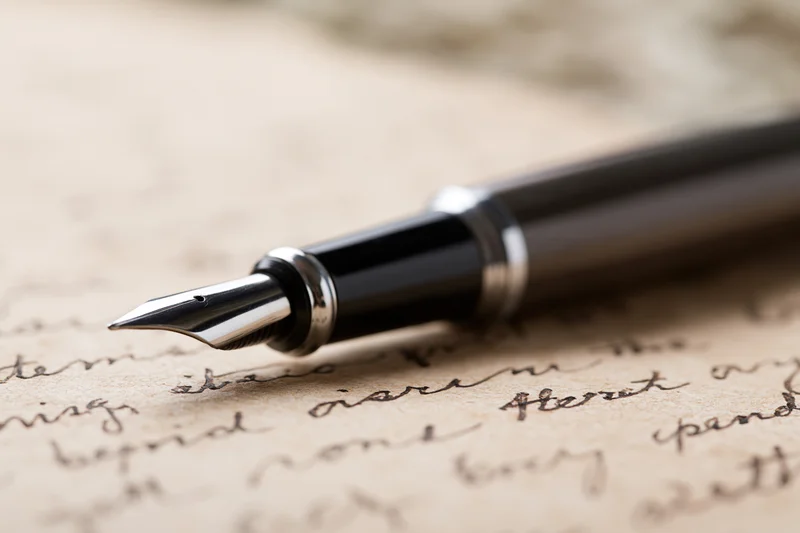 Black and silver fountain pen resting on aged handwritten letter