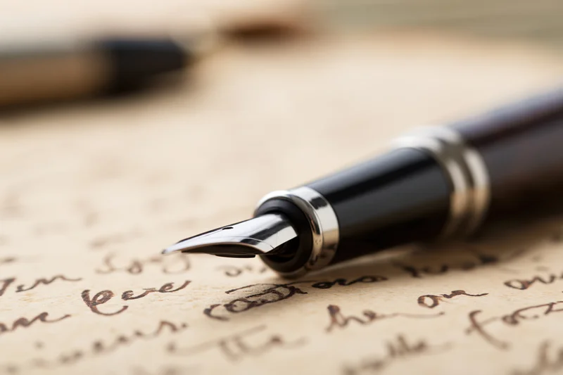 Fountain pen resting on aged handwritten letter with cursive script