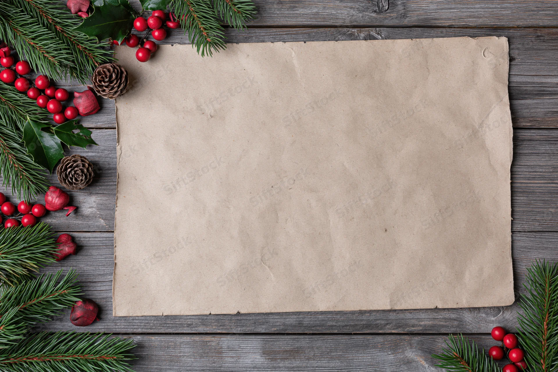 Blank aged kraft paper sheet on weathered wooden surface surrounded by christmas decorations