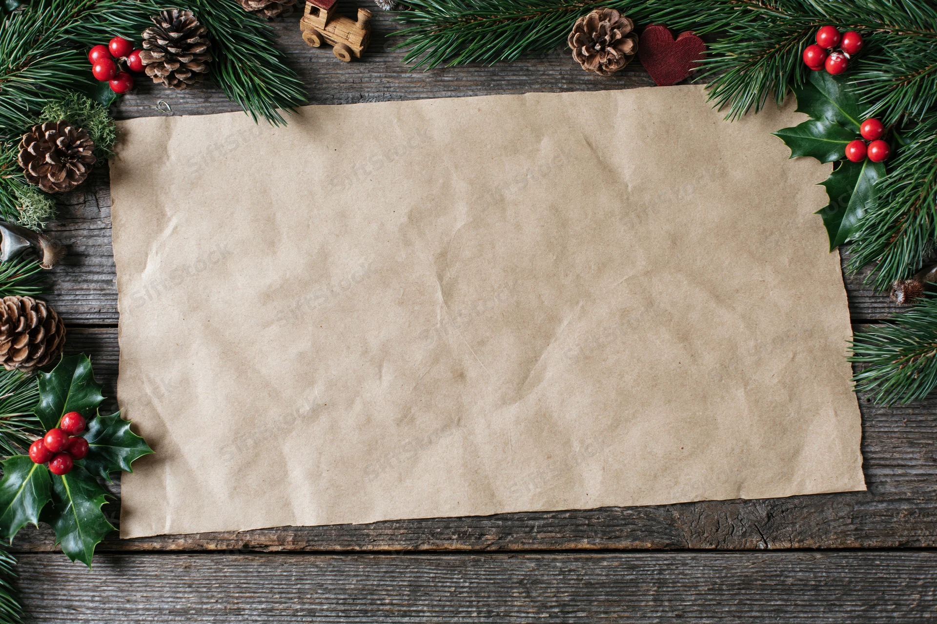 Blank kraft paper sheet on weathered wooden surface surrounded by christmas decorations