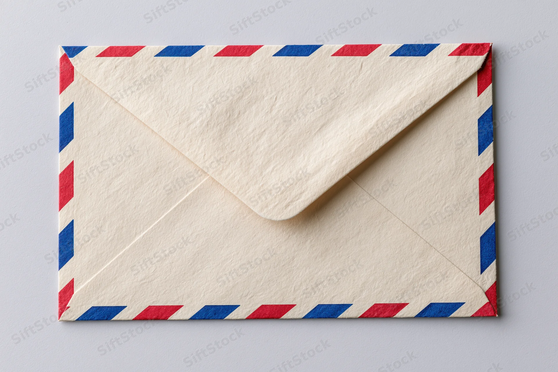 Airmail envelope with red and blue diagonal stripes lying flat on a neutral surface