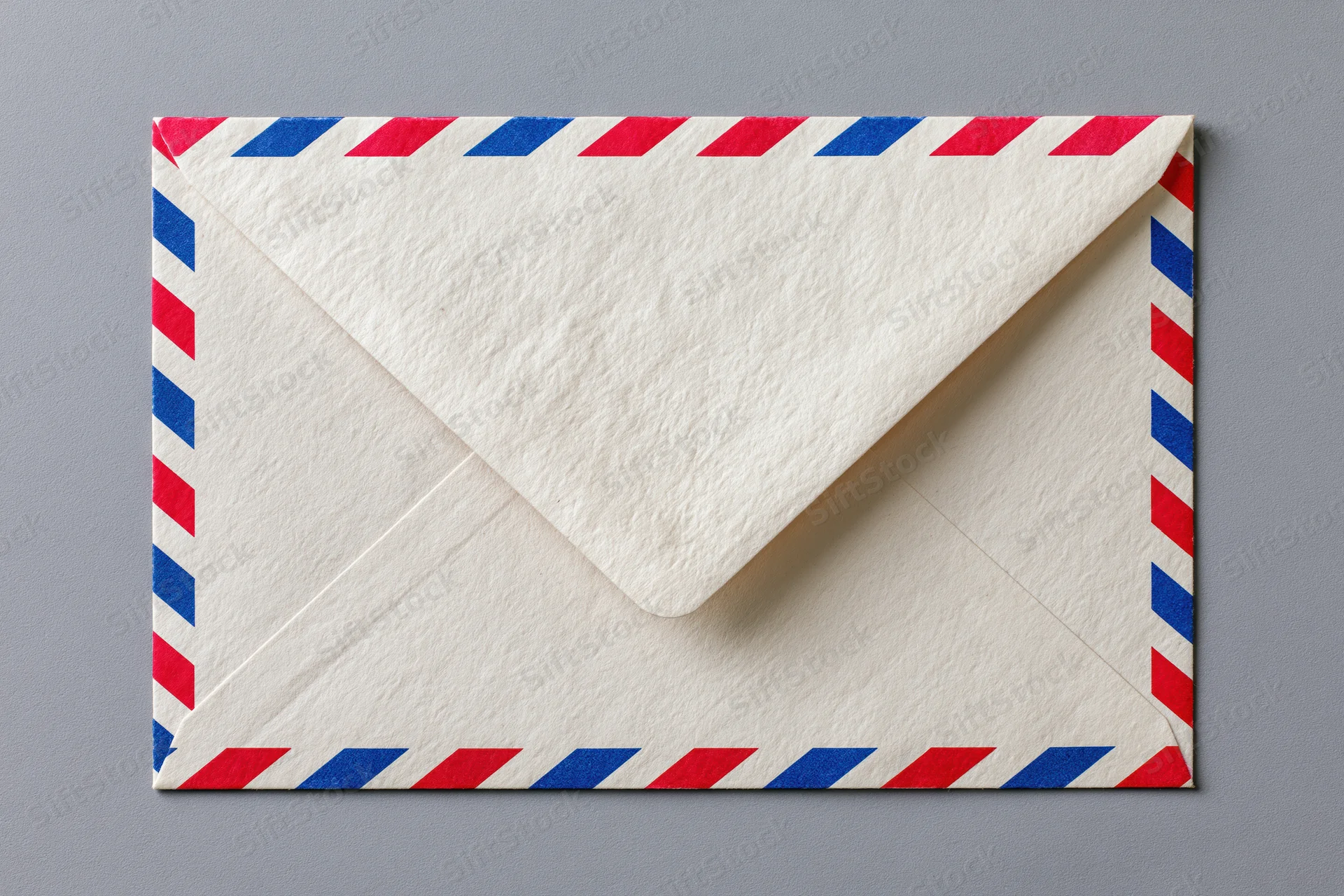 Airmail envelope with red and blue diagonal stripes lying flat on gray surface