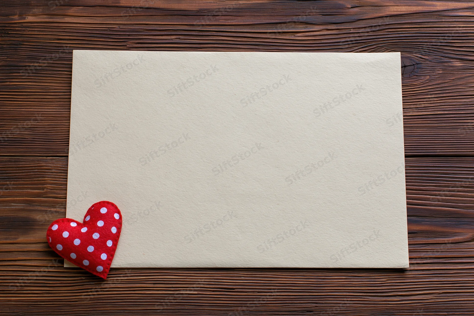 Blank cream paper sheet with red polka dot heart on dark wooden surface