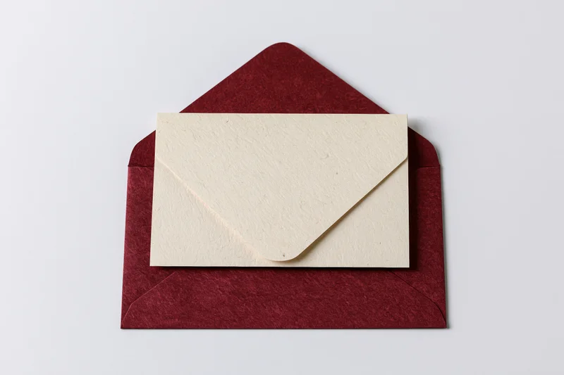 Open red envelope with cream card inside on white surface