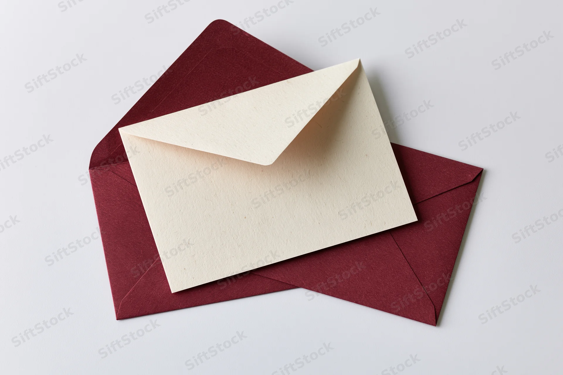 Cream recycled paper card resting on open maroon envelope on white surface