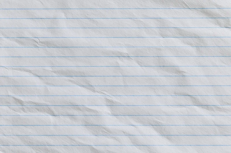 Crumpled lined notebook paper with blue horizontal lines filling the frame