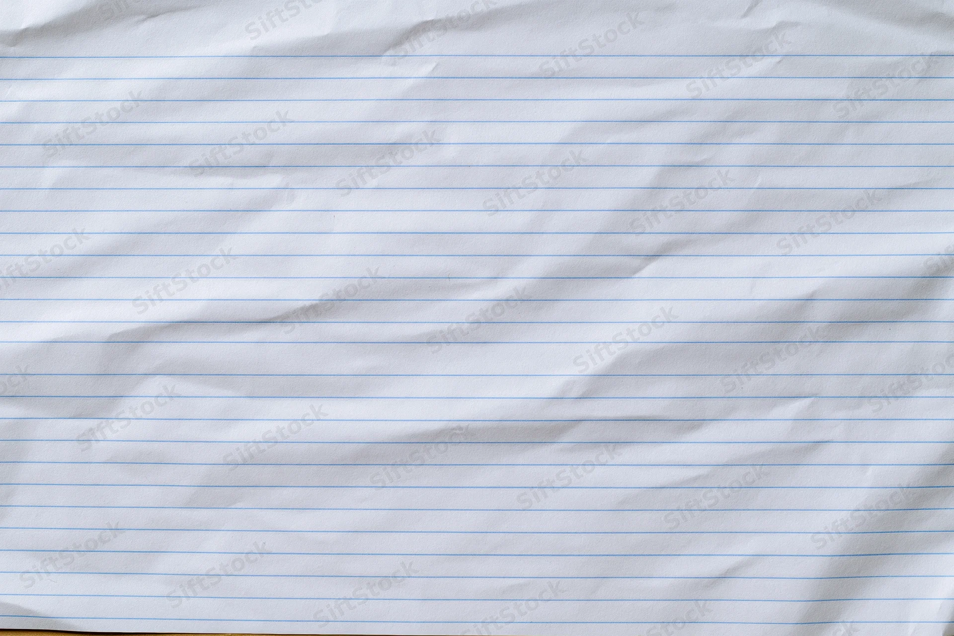 Crumpled lined notebook paper filling the frame with blue horizontal lines