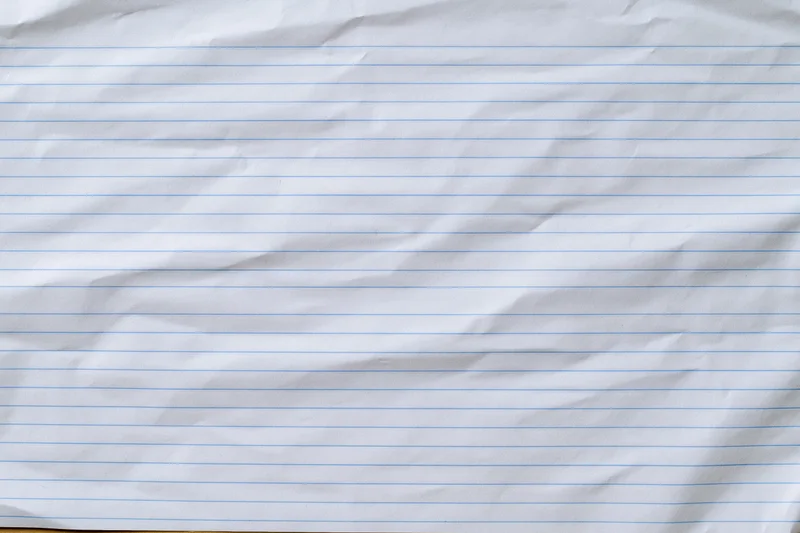 Crumpled lined notebook paper filling the frame with blue horizontal lines