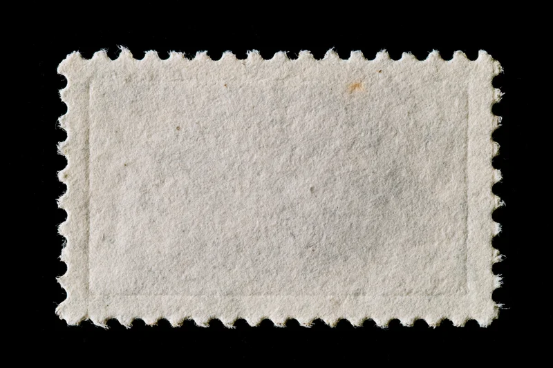 Blank postage stamp with perforated edges on black background