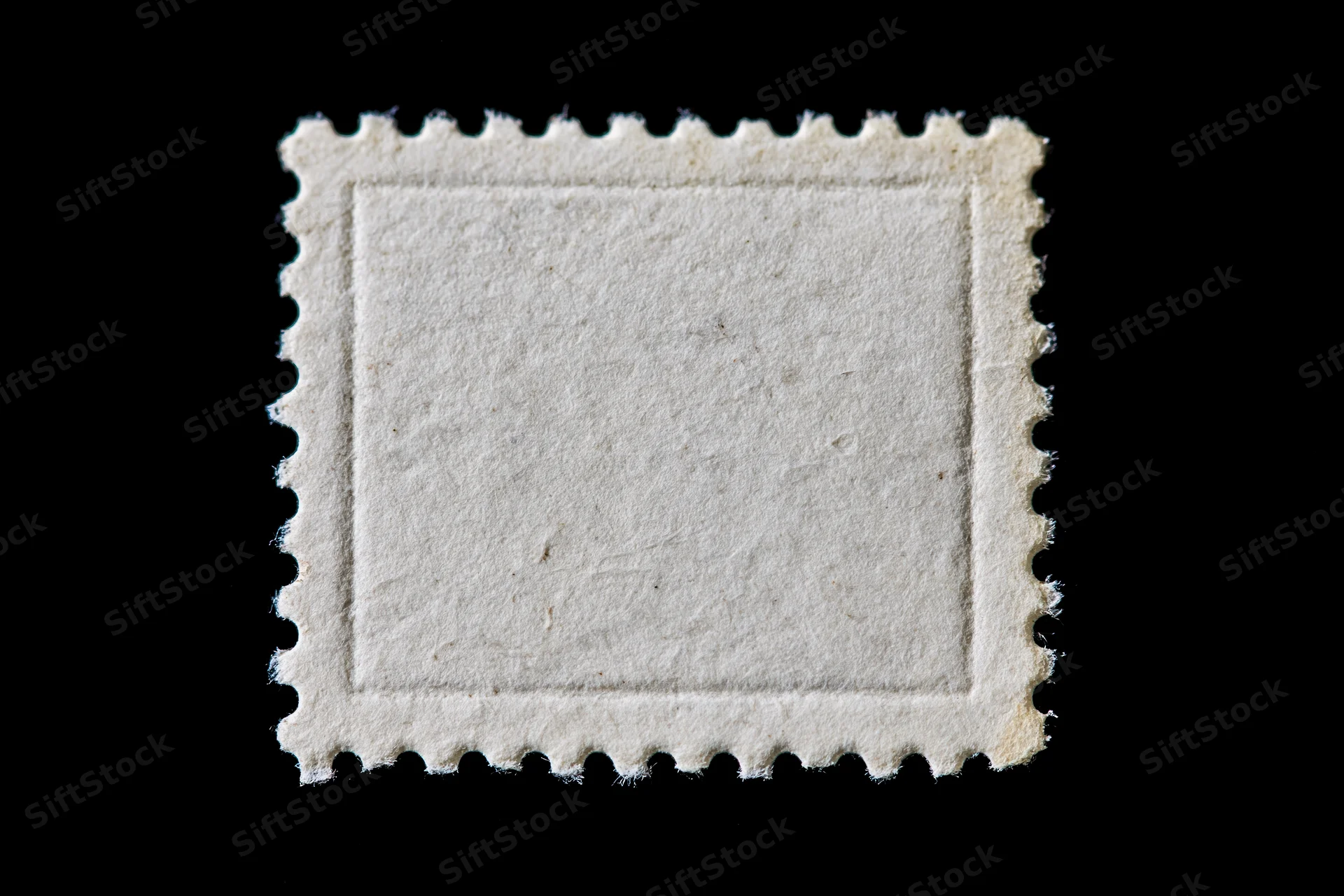 Blank postage stamp with perforated edges on black background