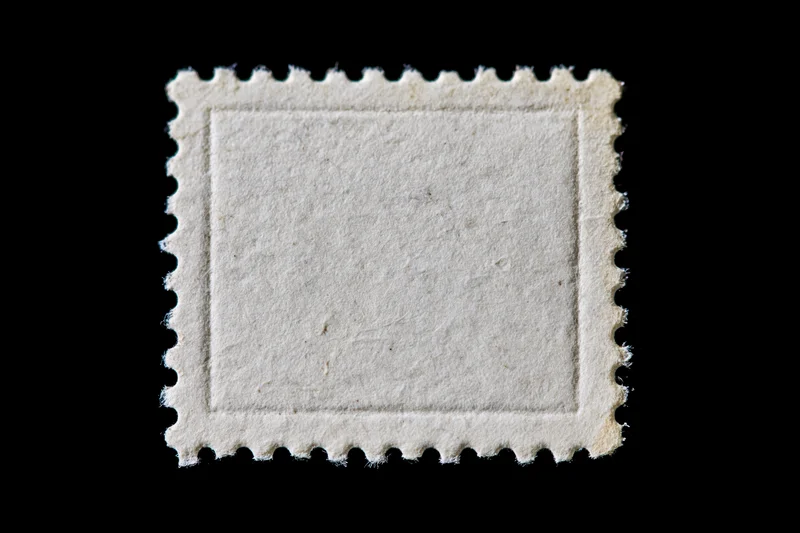Blank postage stamp with perforated edges on black background