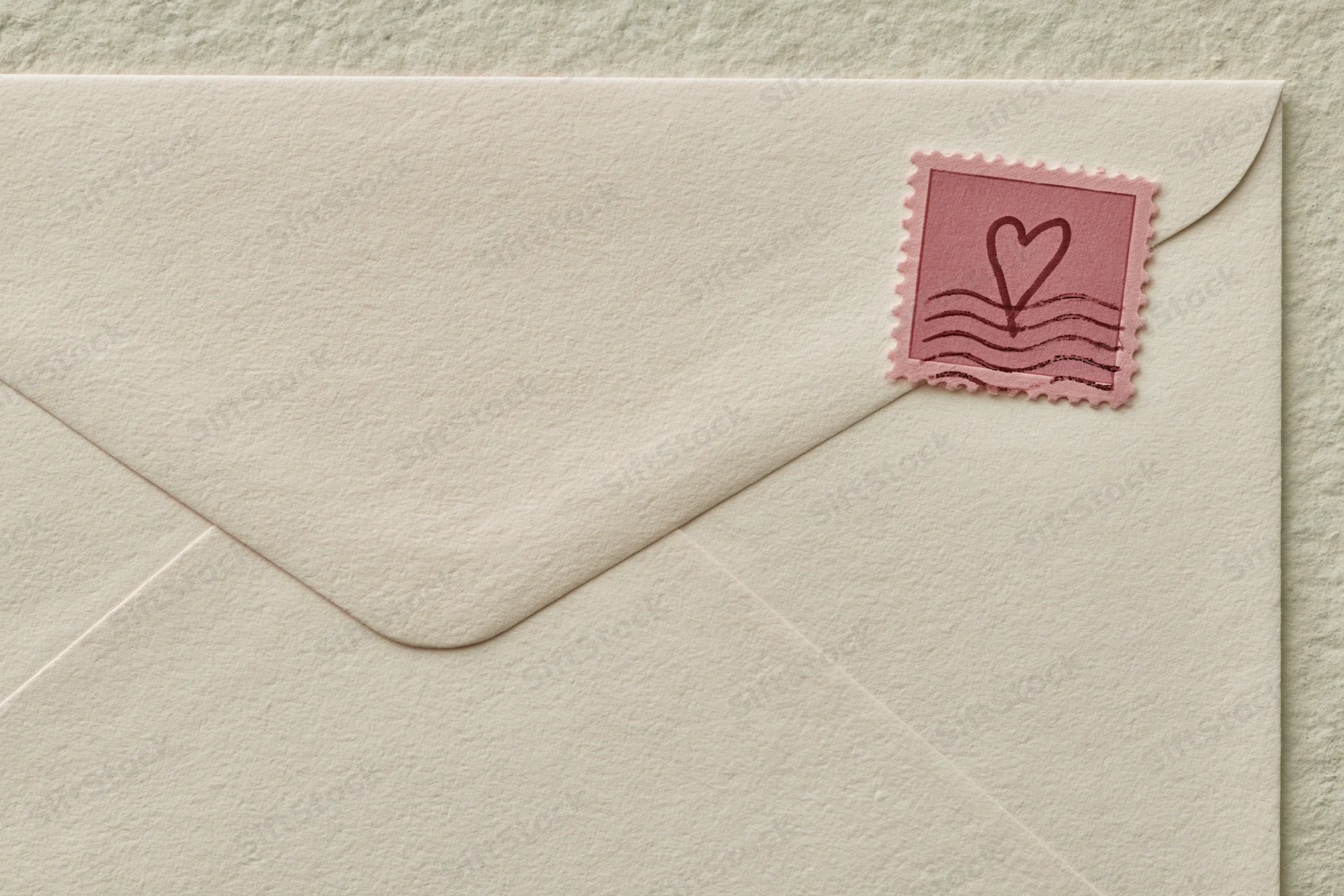 Cream textured vintage envelope with pink heart stamp on flat surface