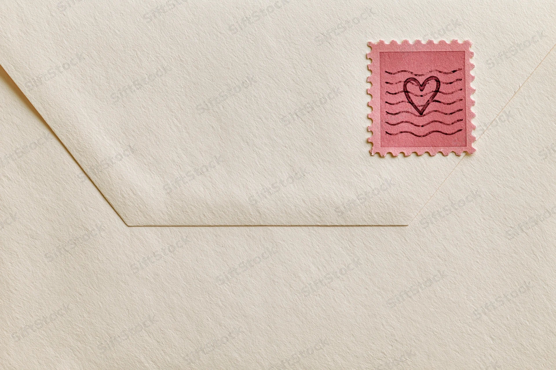 Cream textured vintage envelope with pink heart stamp in corner, flat lay view