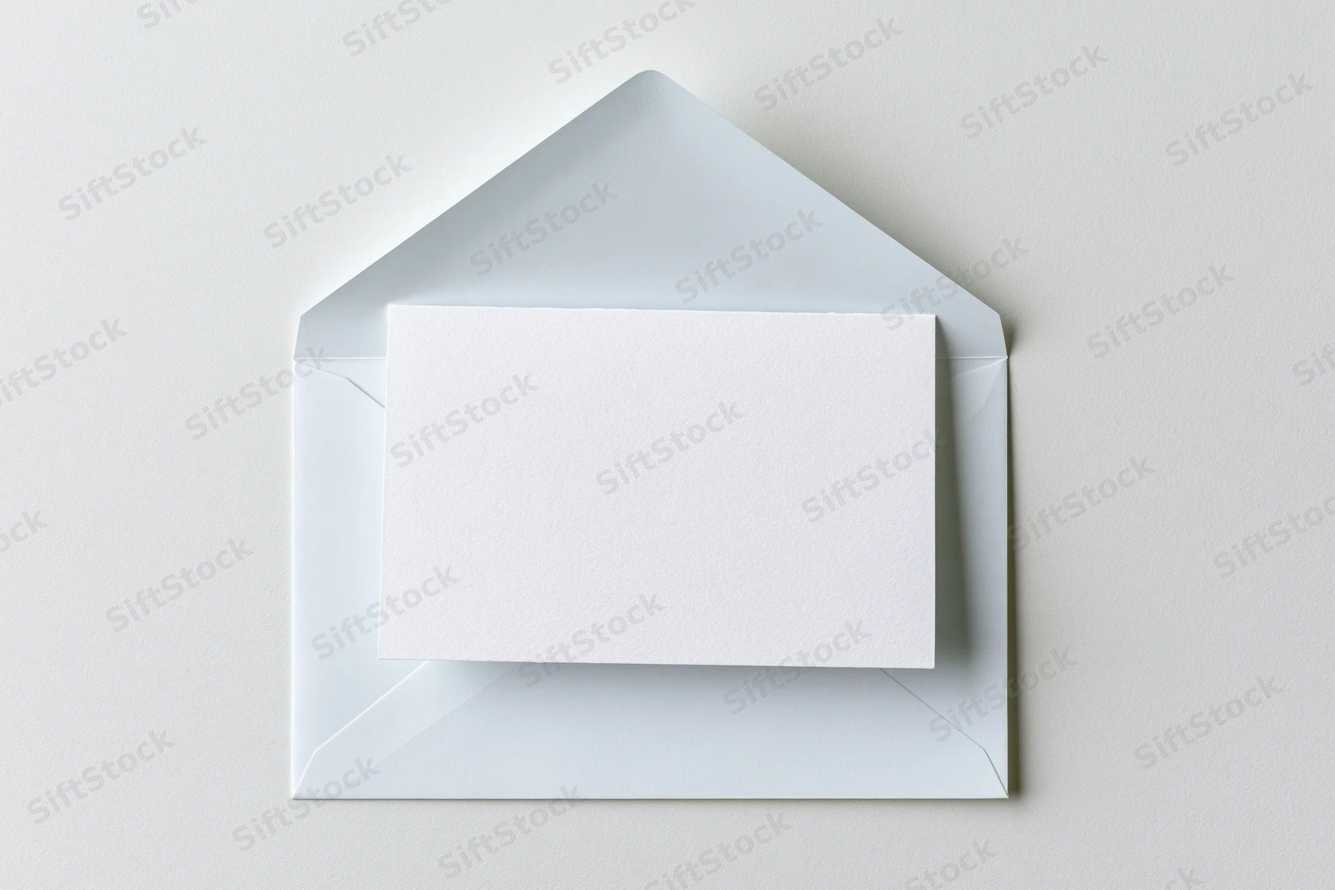 Open white envelope with blank card inside on plain surface