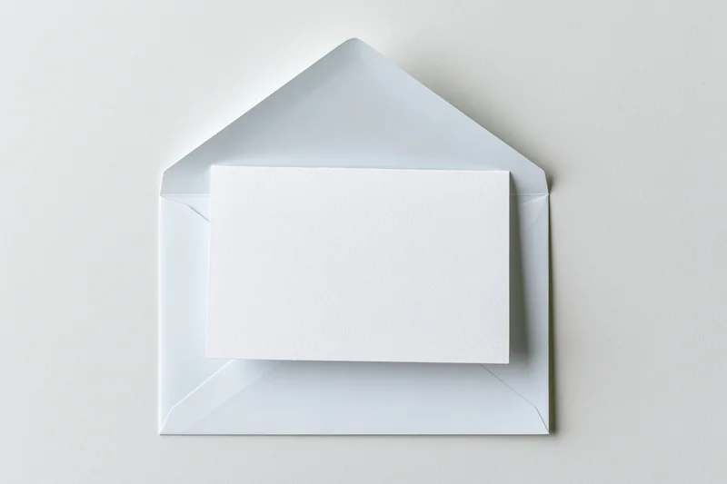Open white envelope with blank card inside on plain surface