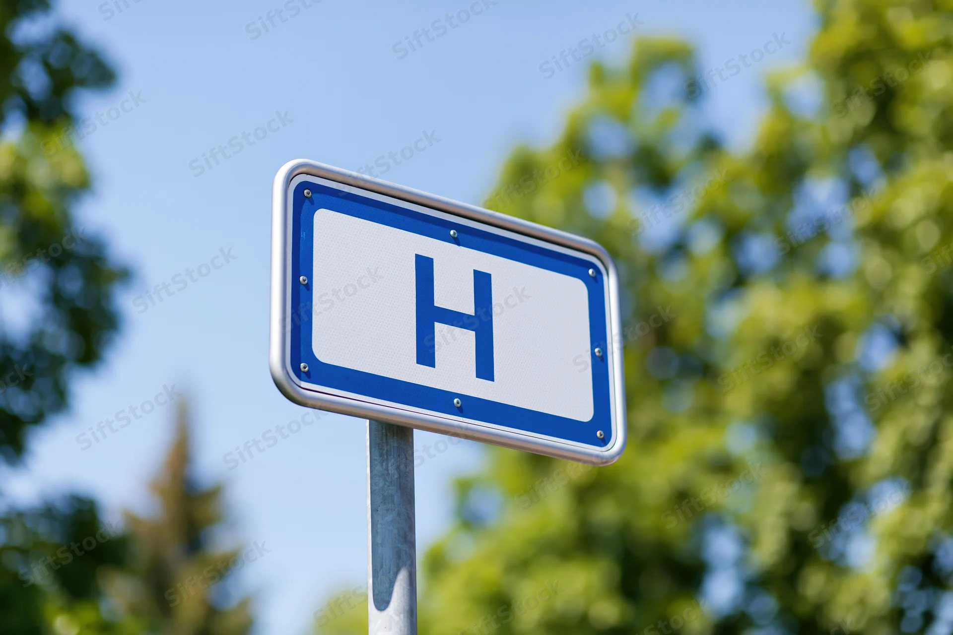 Blue and white hospital directional sign mounted on metal post outdoors