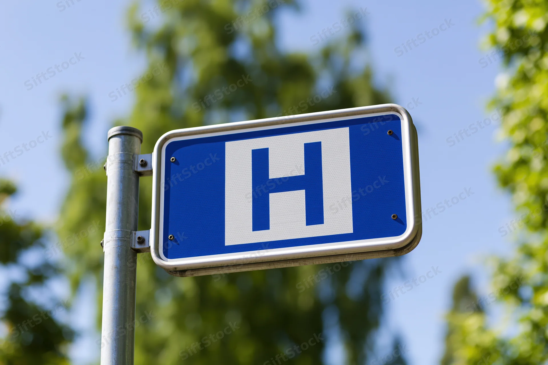 Blue and white hospital directional sign mounted on metal pole outdoors