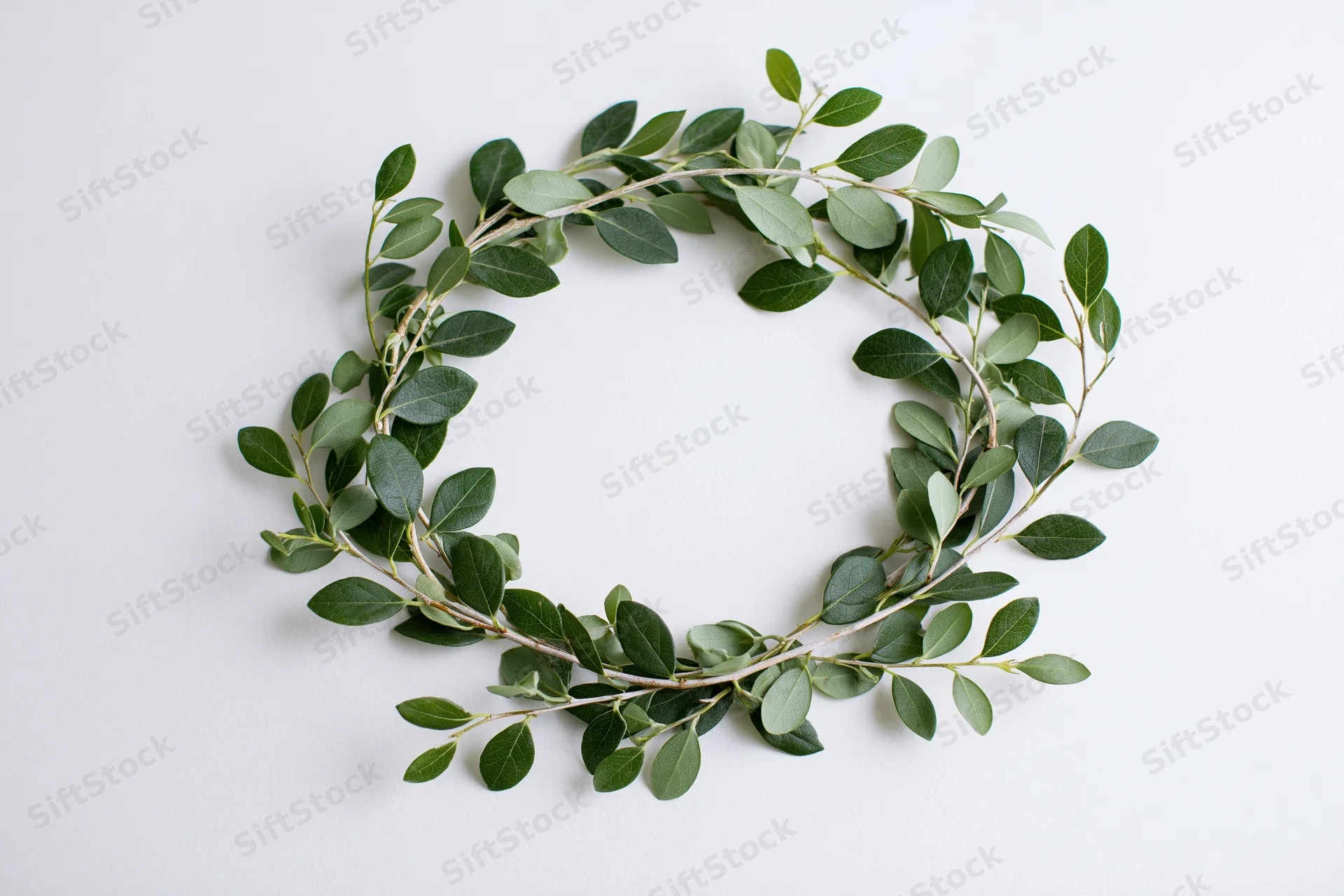 Circular wreath made of small green leaves arranged on white surface