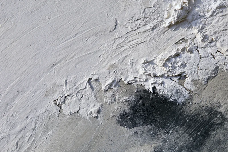 Close-up of abstract painted canvas with textured white gray and black brushstrokes and peeling layers