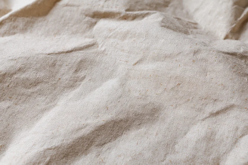 Close-up of crumpled cream kraft fabric texture in flat lay arrangement