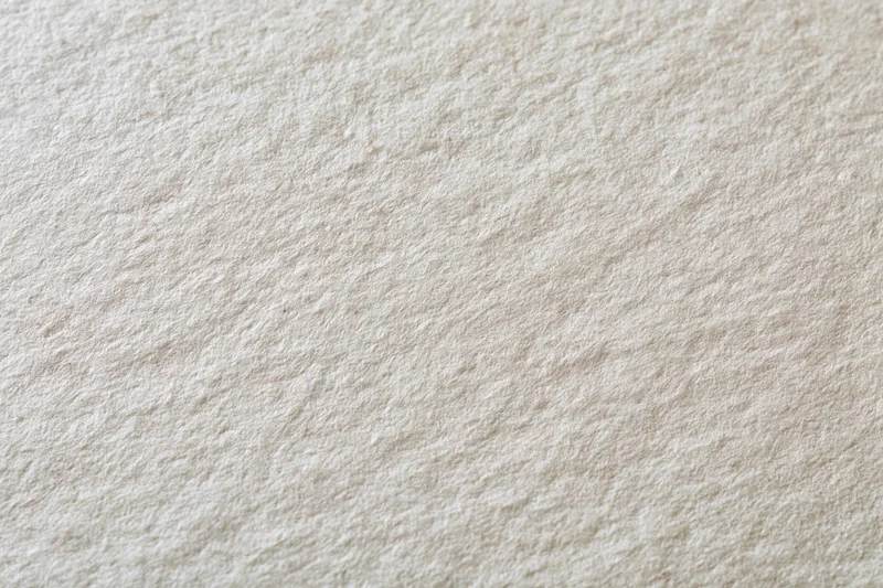 Close-up of aged cream-white paper surface with textured grain filling the frame