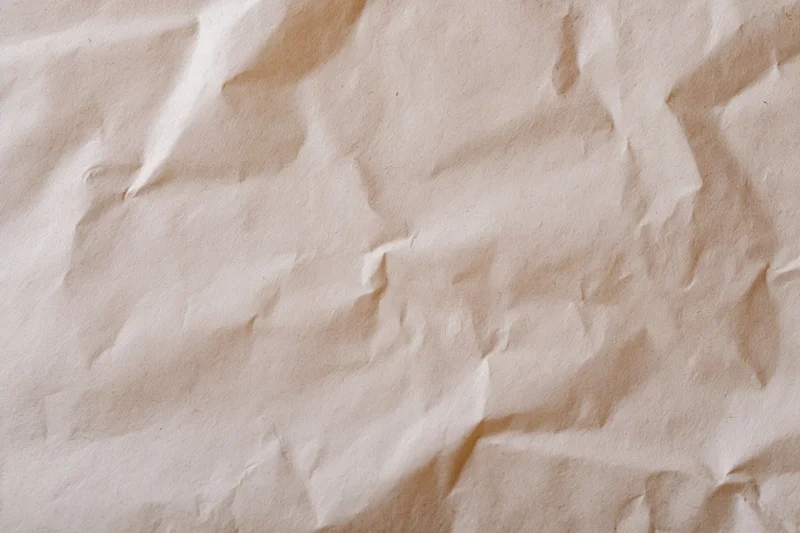 Close-up of crumpled cream wrapping paper with aged texture and soft folds