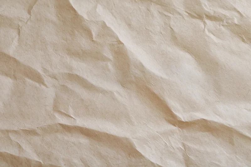 Close-up of crumpled cream wrapping paper with natural texture and folds