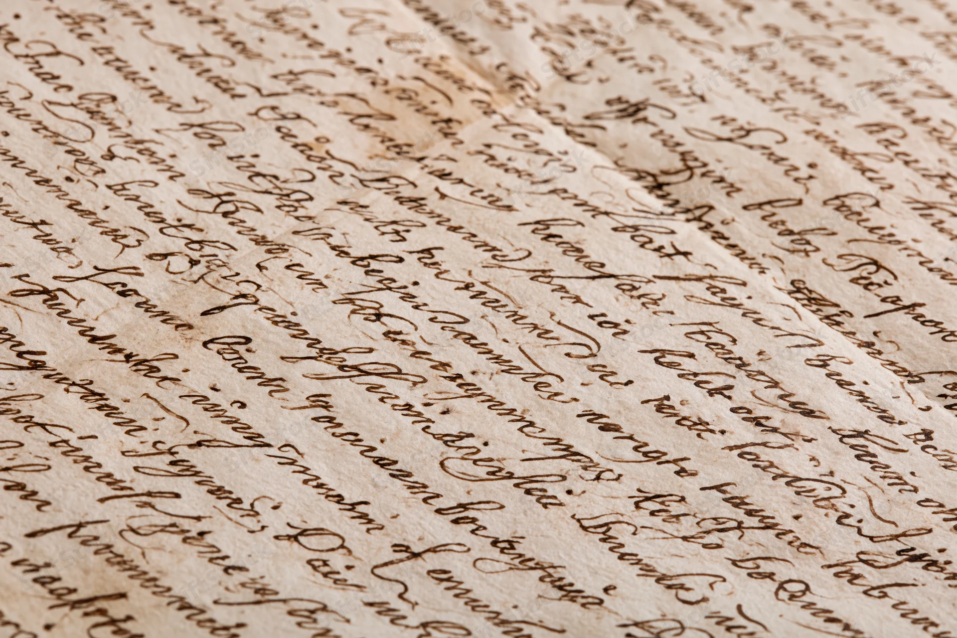 Close-up of aged handwritten manuscript paper with cursive script and visible folds