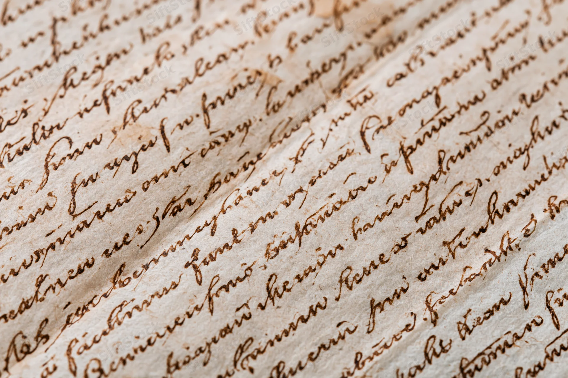Close-up of aged handwritten manuscript paper with cursive script and visible folds