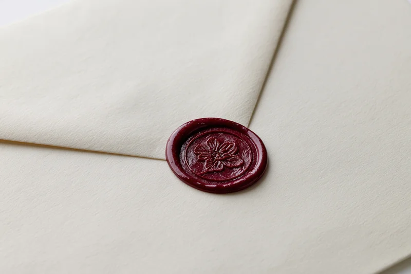 Cream-colored envelope sealed with a deep red wax seal featuring a floral imprint