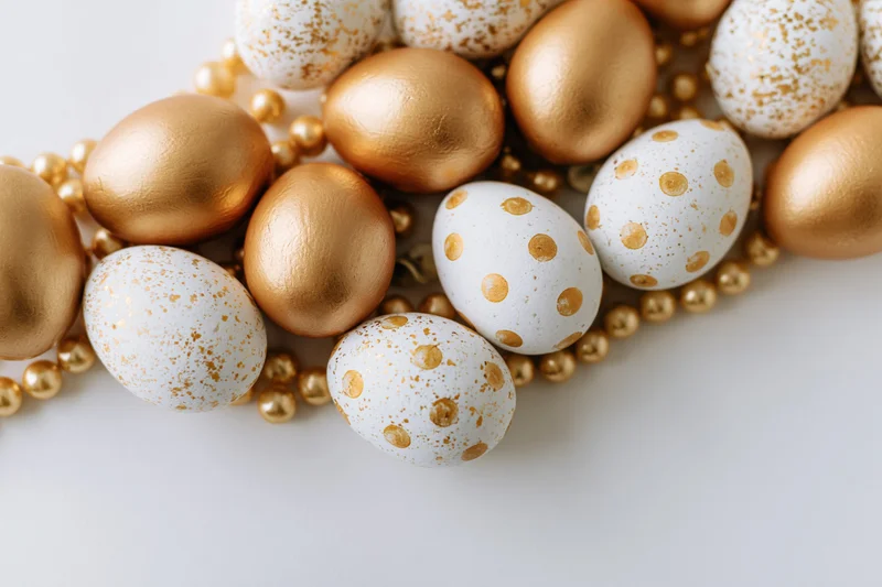 Decorated easter eggs with golden and white polka dot patterns arranged along the right edge on a white surface