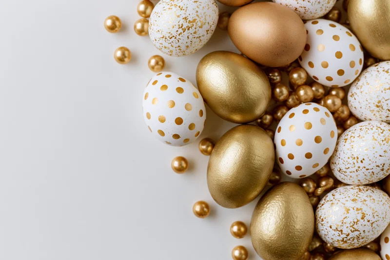 Decorated easter eggs with gold polka dots and speckles arranged along the right edge on a white surface