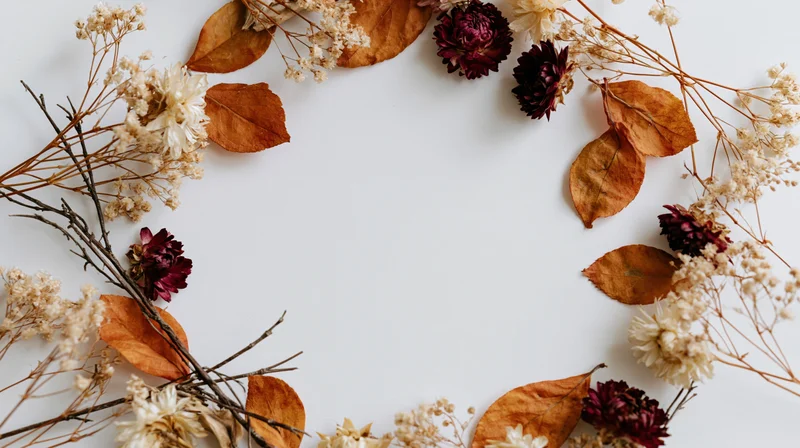 Dried autumn botanicals arranged in a loose wreath on white background with copyspace