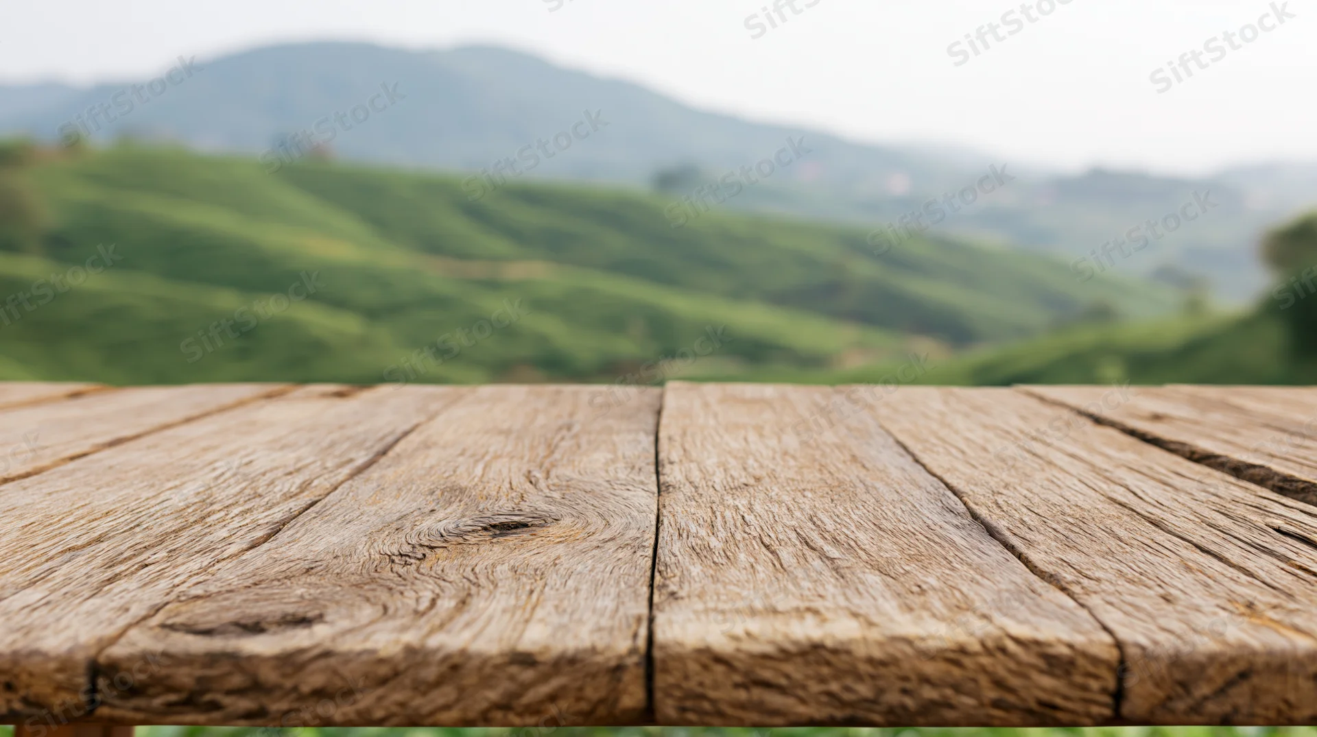 Weathered wooden table surface in front of a green tea plantation landscape