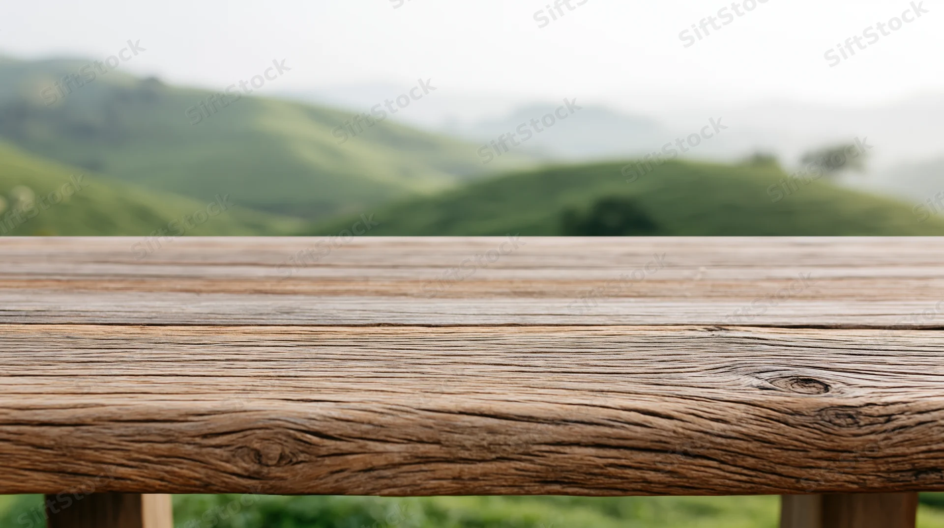 Weathered wooden table surface in front of rolling green hills