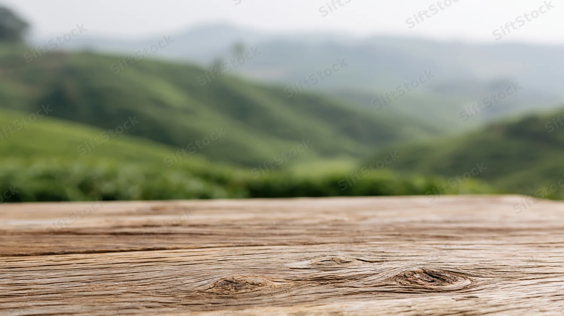 Weathered wooden table surface in front of green rolling hills landscape
