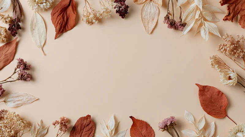 Dried autumn leaves and botanicals arranged in a flat lay frame on a beige surface