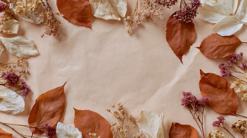 Dried autumn leaves and botanicals arranged in a circular frame on textured paper with central copyspace