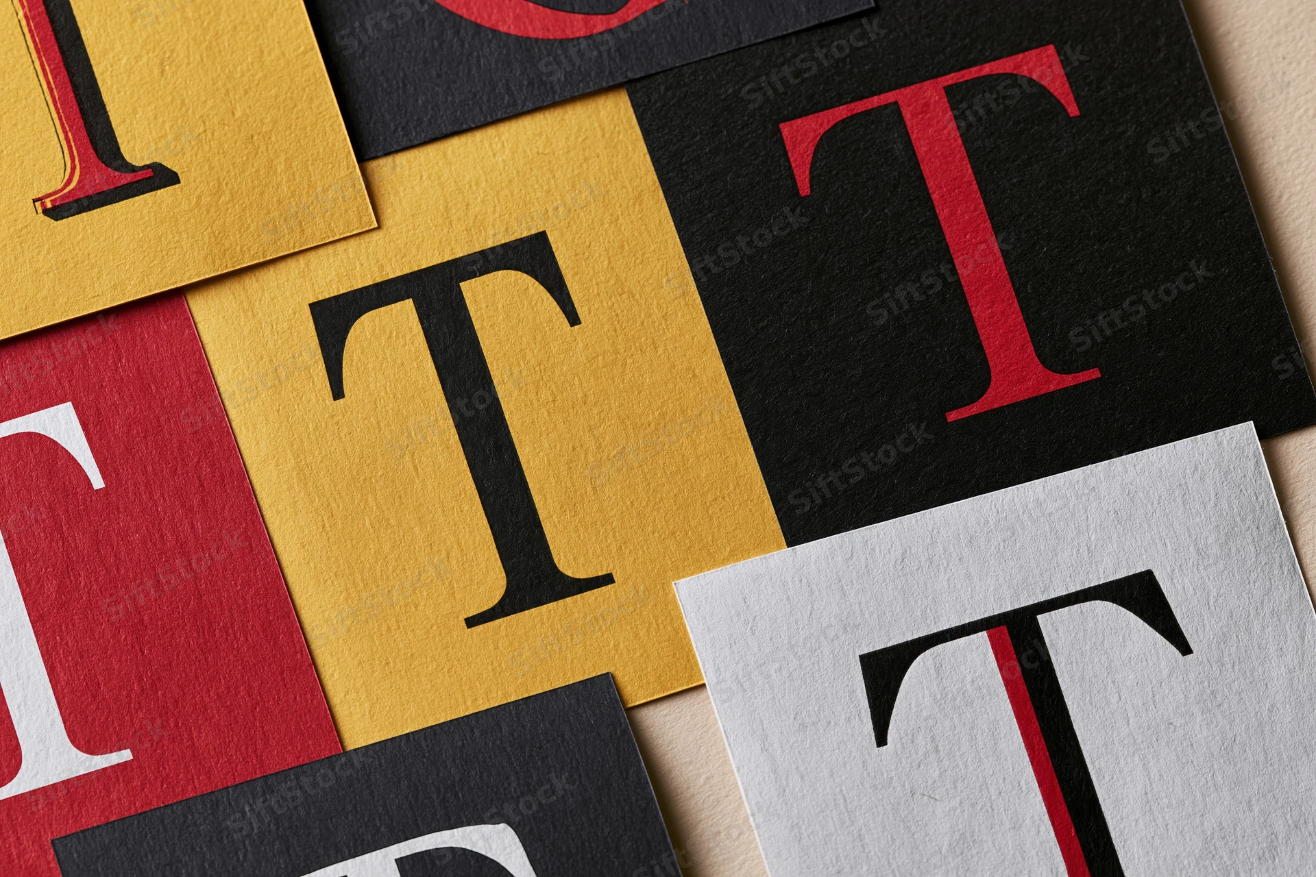 Flat lay of cut paper squares with letter t in various colors and fonts arranged in a collage