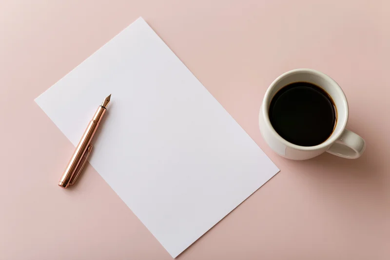 Blank white paper with rose gold fountain pen and coffee mug on pink surface