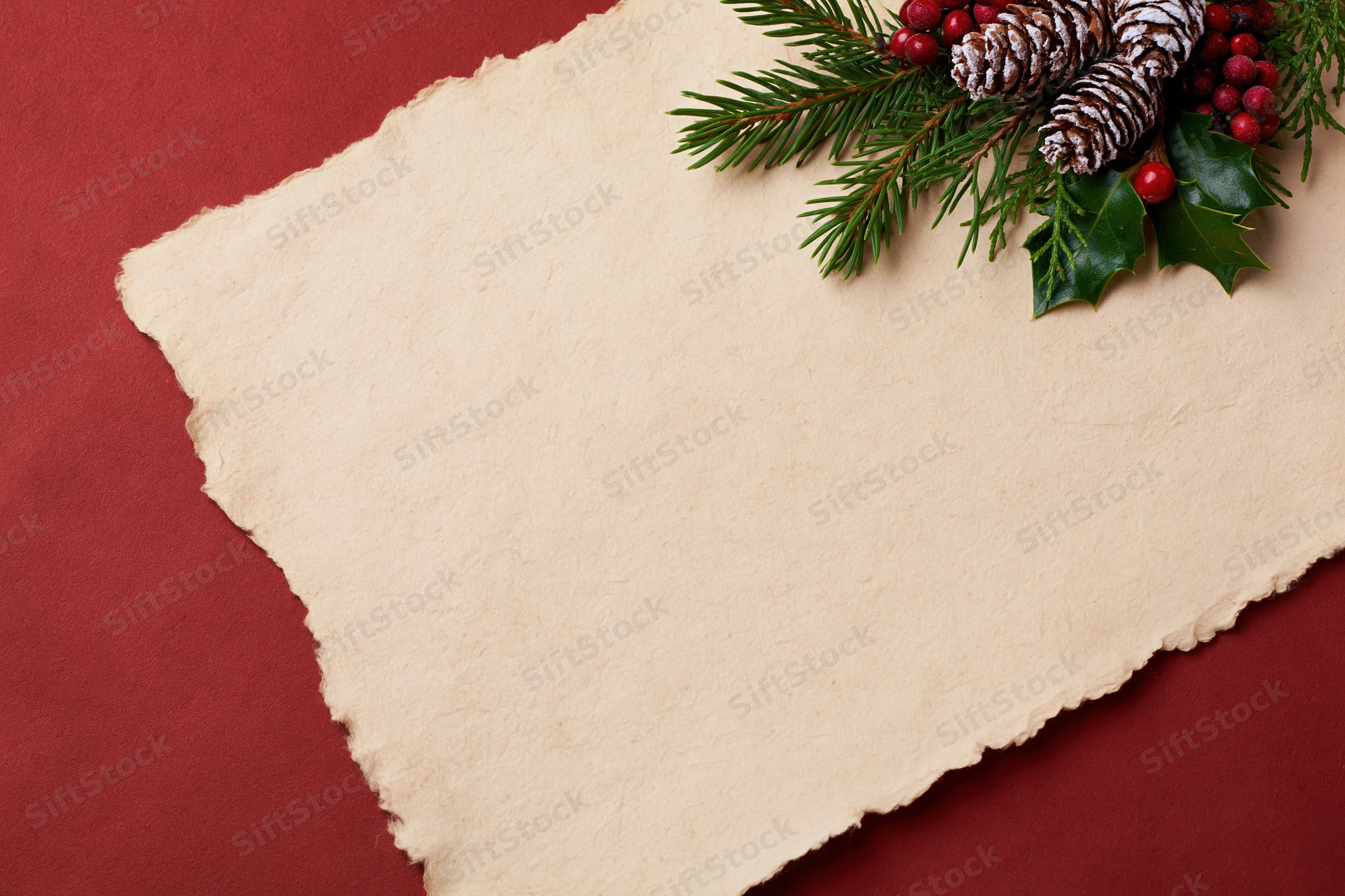 Aged parchment paper with torn edges and christmas decorations on red background