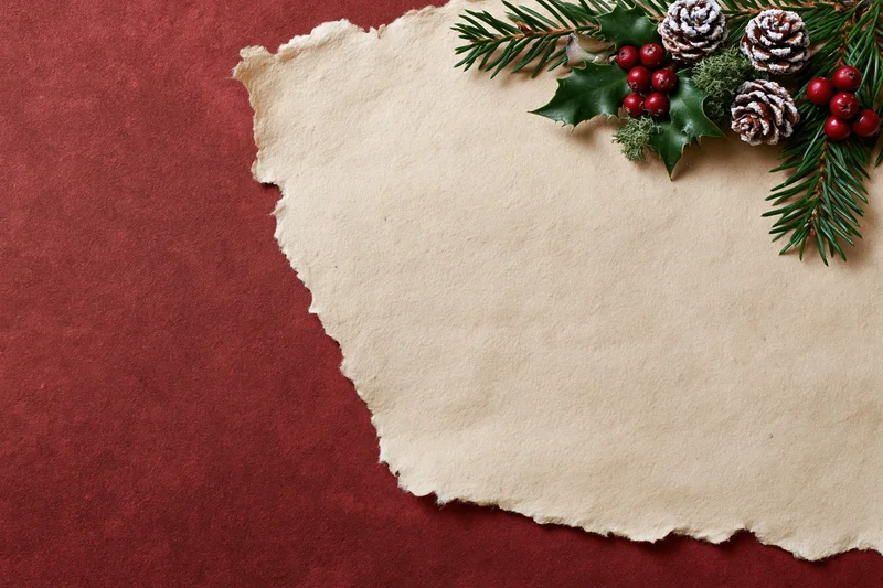Torn parchment paper with evergreen sprigs and holly berries on red background
