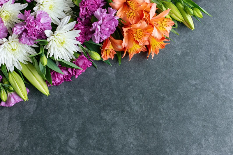 Mixed spring flowers arranged in a flat lay on a gray surface with copyspace