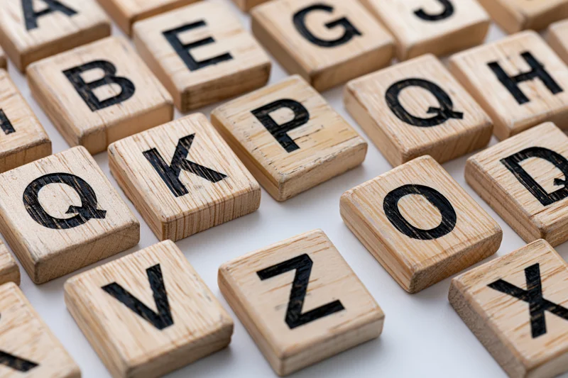 Wooden letter tiles arranged in alphabetical grid on white surface