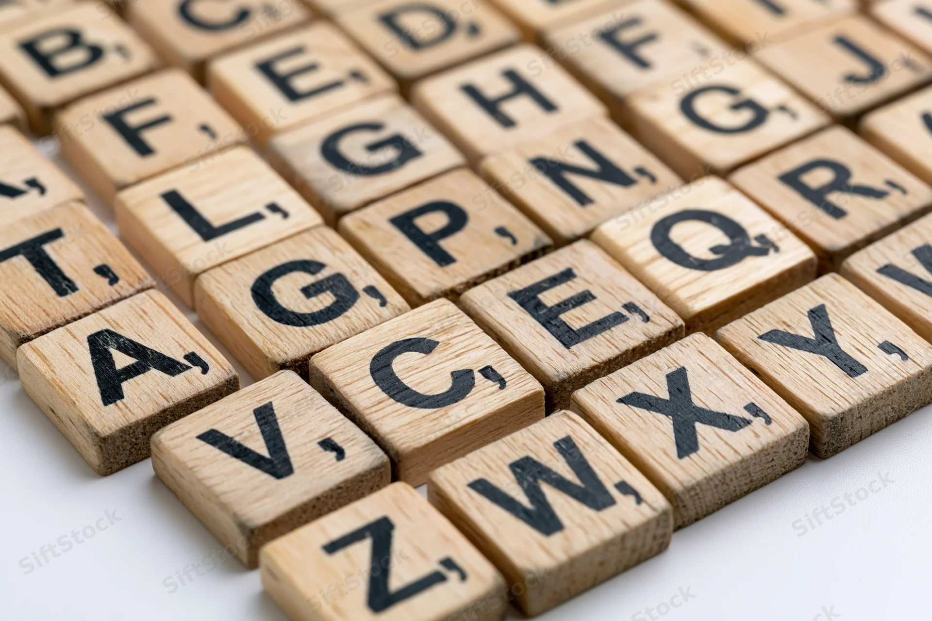 Wooden letter tiles arranged in alphabetical grid on white surface