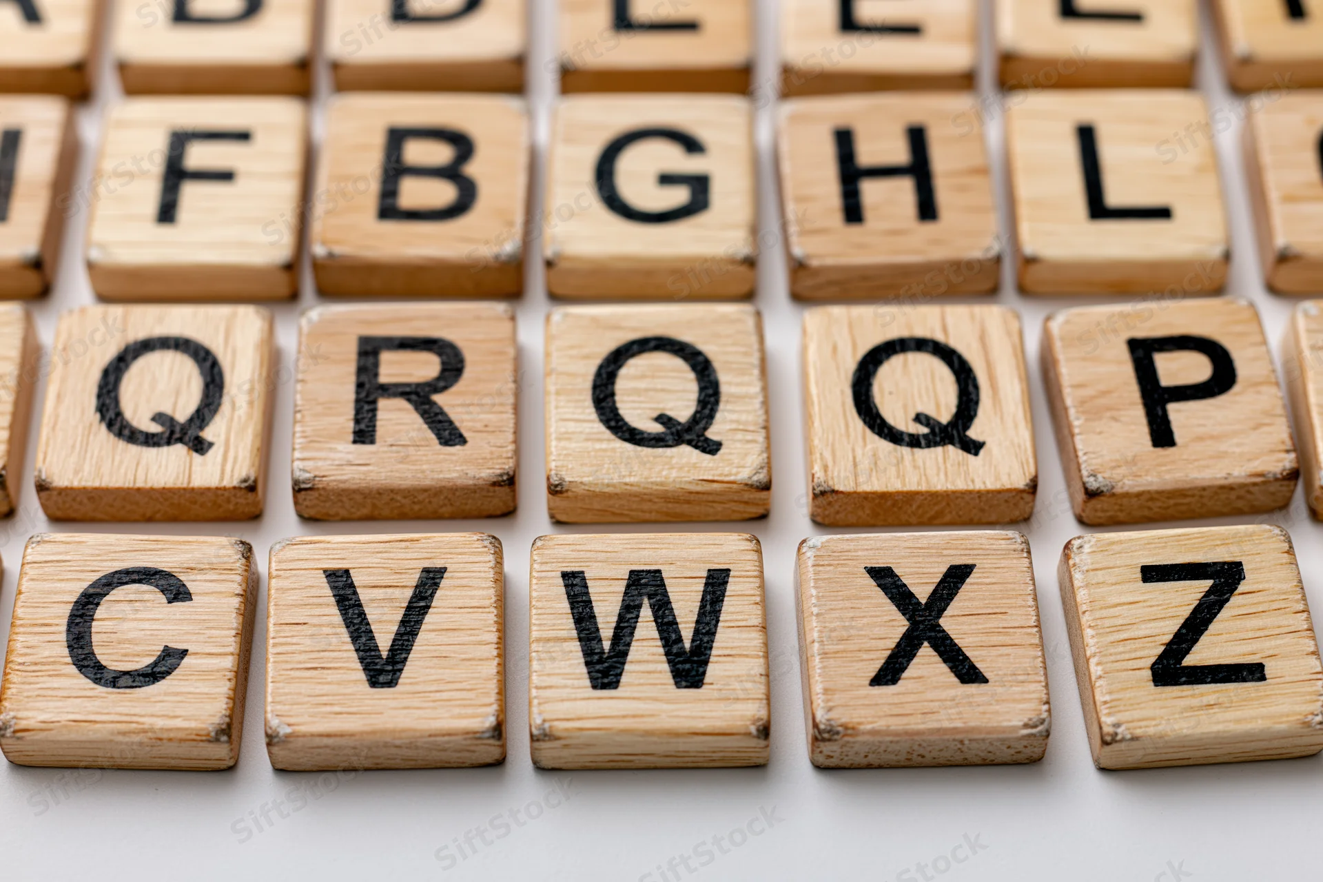 Wooden letter tiles arranged in alphabetical grid on light surface