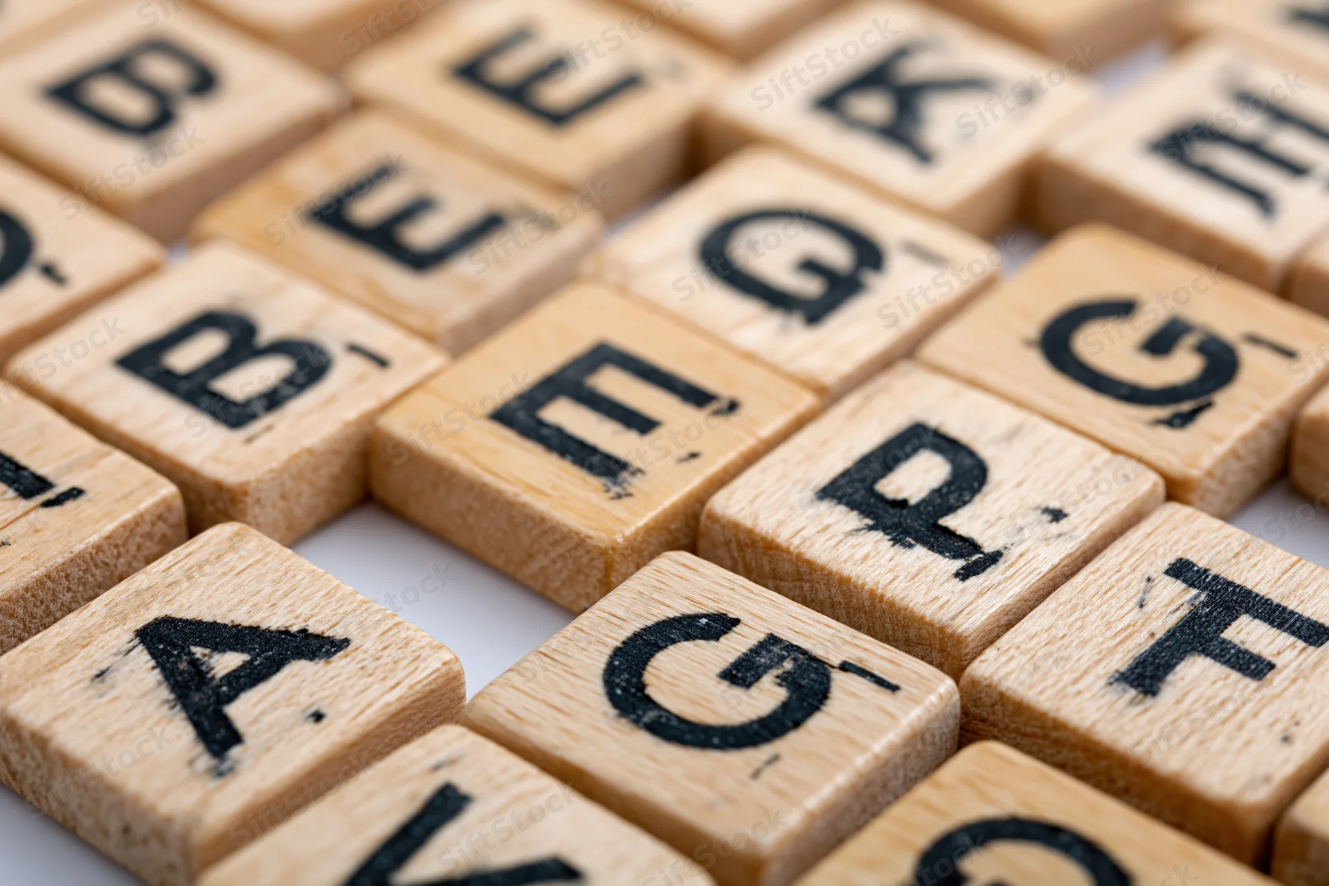 Wooden letter tiles arranged in alphabetical grid on white surface