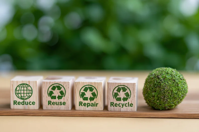 Four wooden cubes with reduce reuse repair recycle text and green moss ball on wooden surface