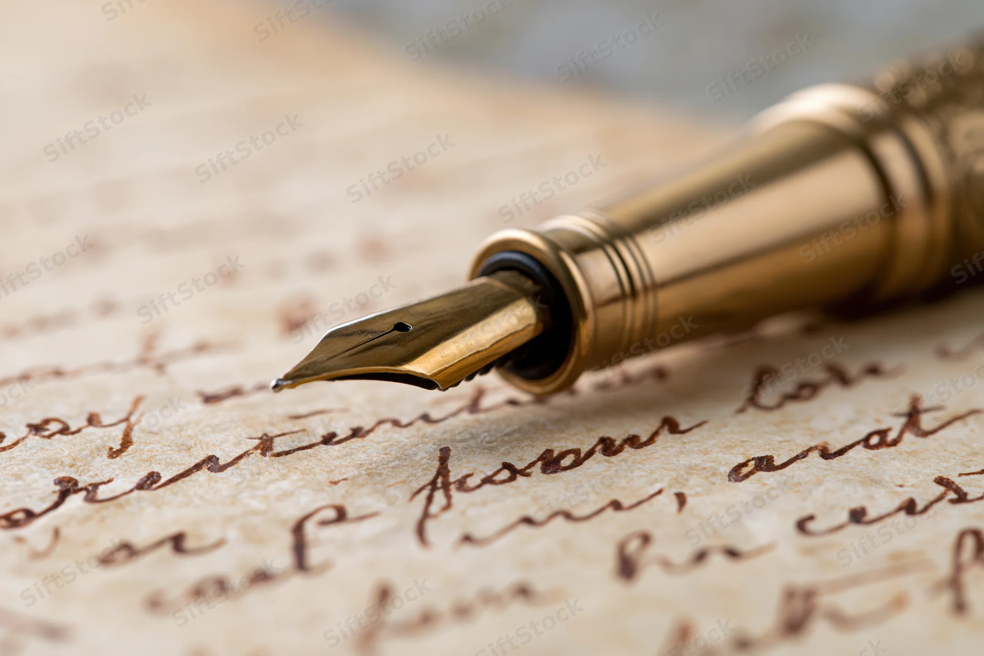 Gold fountain pen resting on aged handwritten letter with cursive script