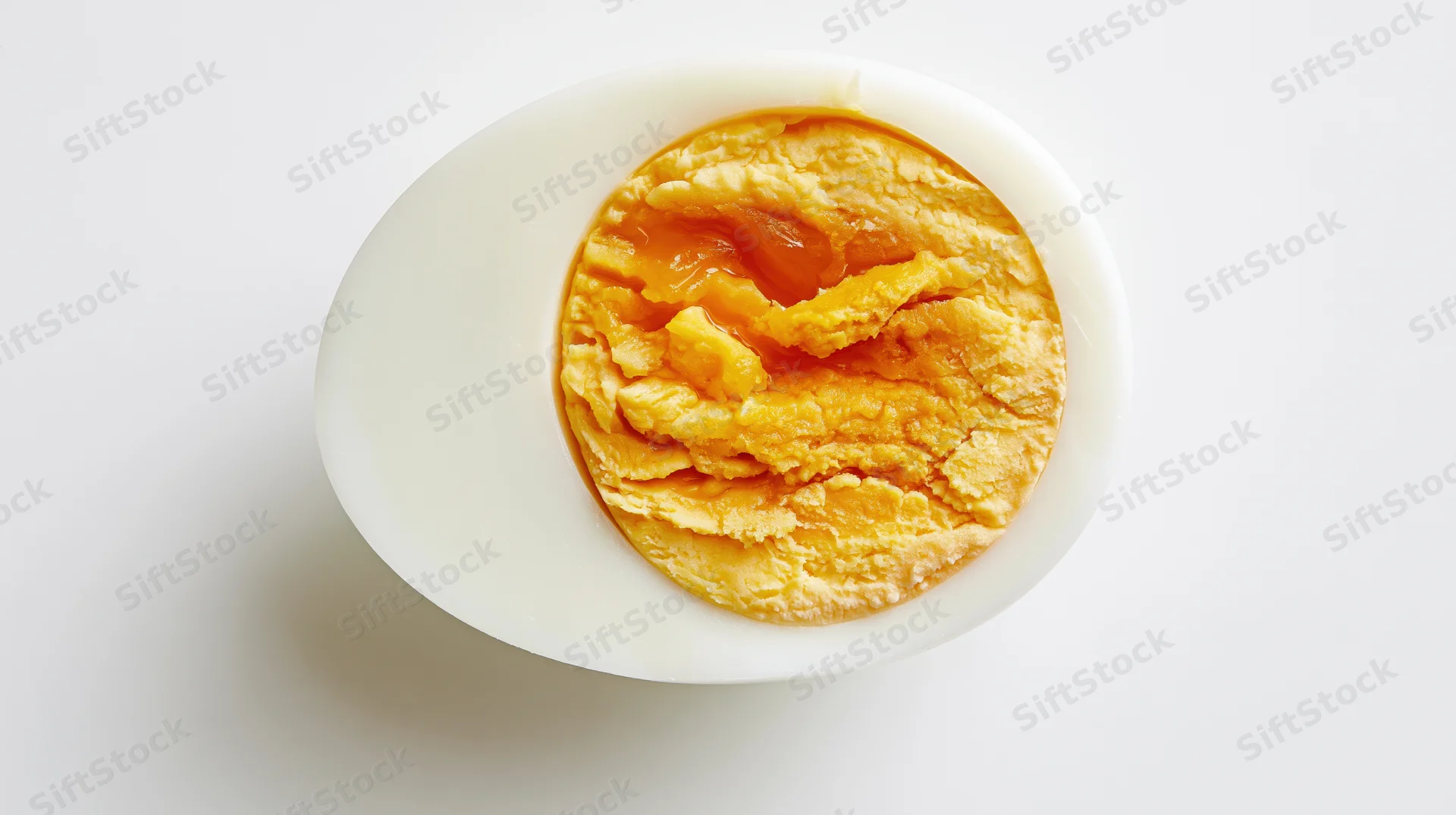 Half of a hard-boiled egg sliced crosswise showing yolk and white on white background